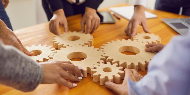 A-group-of-company-employees-aligning-wooden-gears-to-symbolize-business-strategy-and-innovation